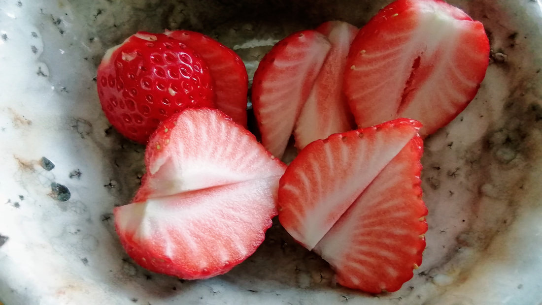 fresh strawberries in a bowl, sliced in half